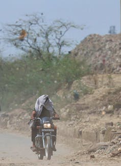 A man rides his bike near a landfill site on a hot summer day during a heatwave in New Delhi, India, May 27, 2024.