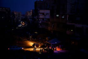 Palestinians gather amid power cut near houses damaged during Israel's military offensive, in Khan Younis, in the southern Gaza Strip, May 28, 2024.