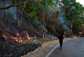 A journalist wears mask near a forest fire in Samoeng District, Thailand April 4, 2019.