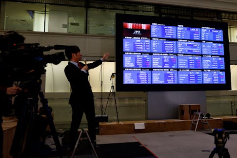 A TV reporters points a closing price of Nikkei index on a stock quotation board after a ceremony marking the end of trading in 2023 at the Tokyo Stock Exchange (TSE) in Tokyo, Japan December 29,  2023.