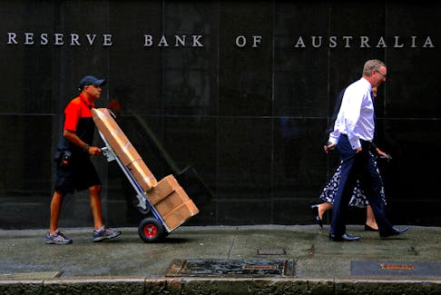 A worker pushing a trolley walks with pedestrians past the Reserve Bank of Australia (RBA) head office in central Sydney, Australia, March 7, 2017.