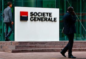 People walk past a logo of French bank Societe Generale in front of the company's skyscraper at the financial and business district of La Defense near Paris, France September 14, 2023.