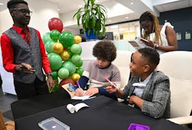Published authors, from left, Maichail Reid, Sam Akao, Amani Mutuku (back) and Santeano Barrows autograph copies of their book, Windows & Mirrors, at the recent launch event in Coldbrook.   
– Contributed