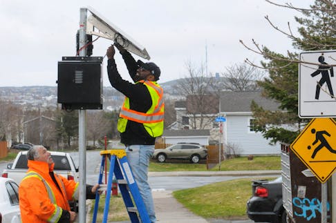 The City of Mount Pearl is part of a pilot project and currently installing speed cameras in various areas of the city. Shown here is a Guardian Pro speed camera being installed on Michener Avenue, which is near a few schools on Ruth Avenue. Chris Blundon, left, of Construction Signs of Paradise, whose company installed the cameras, assists Keins Rajaratnam (on ladder) of Montreal-based Traffic Logistics as they get the camera ready for operational mode. - Joe Gibbons/The Telegram