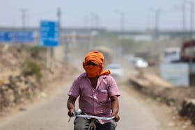 A man rides his cycle near a landfill site on a hot summer day during a heatwave in New Delhi, India, May 27, 2024.