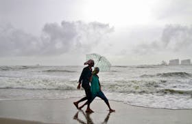 Beachgoers react to the camera while holding an umbrella as it drizzles at the Fort Kochi beach in the southern Indian city of Kochi June 6, 2014.