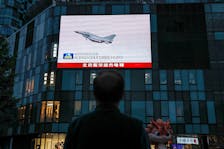 A man looks at a giant screen showing news footage of military drills conducted in areas around the island of Taiwan by the Eastern Theatre Command of the Chinese People's Liberation Army (PLA), in Beijing, China May 24, 2024.