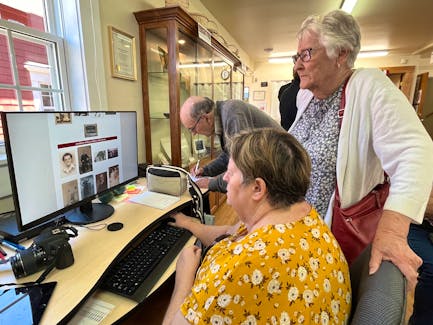 Ina Amirault (seated) and Joyce d’Entremont browse through one of the new digital exhibits at the West Pubnico Museum, while Coral d’Entremont fills out a scavenger hunt form during the pre-launch event at the museum on May 29. Kathy Johnson