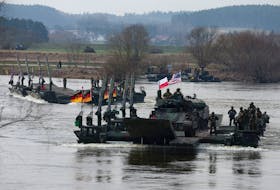 German soldiers transport U.S. soldiers in an M2 Bradley infantry fighting vehicle as they cross Vistula River during NATO Dragon-24, part of the Steadfast Defender 2024 exercise, in Korzeniewo, Poland, March 4, 2024.