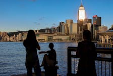 Tourists relax by the Victoria Harbour waterfront, with the iconic skyline providing a scenic backdrop, in Hong Kong, China, July 10, 2023.