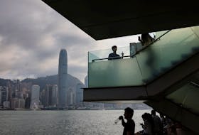 Mainland Chinese tourists look out at the skyline of buildings at Tsim Sha Tsui, in Hong Kong, China May 2, 2023.