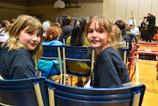 Grade 4 Greenfield Elementary School students Ally MacDonald, left, and Cali Fraser wait for the start of a Music Monday concert at Shipyard Elementary School in Sydney on Monday. Three concerts were done which featured the Cape Breton Orchestra and Mi'kmaq artists. NICOLE SULLIVAN/CAPE BRETON POST