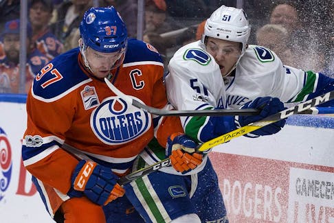 Edmonton Oilers captain Connor McDavid (97) battles the Vancouver Canucks' Troy Stecher (51) in this file photo from Rogers Place in Edmonton on March 18, 2017. The Oilers traded for Stecher with the Arizona Coyotes on Thursday.