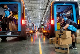 Workers load packages into Amazon Rivian electric trucks at an Amazon facility in Poway, California, U.S., November 16, 2022. 