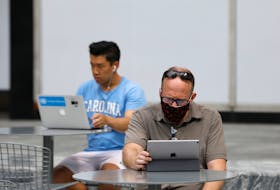 People use an Apple laptop computer and an Apple iPad in Manhattan, New York City, U.S., August 25, 2020.