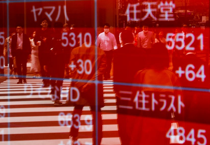 Passersby are reflected on an electric stock quotation board outside a brokerage in Tokyo, Japan April 18, 2023. 
