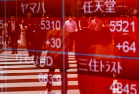 Passersby are reflected on an electric stock quotation board outside a brokerage in Tokyo, Japan April 18, 2023. 