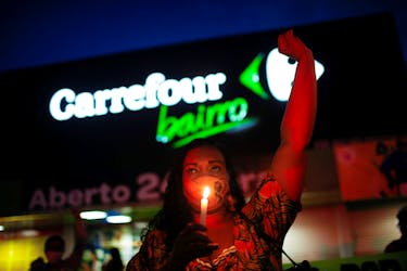 A woman holds a candle during a protest in front of a Carrefour supermarket in Brasilia, Brazil, after Joao Alberto Silveira Freitas was beaten to death by security guards at a Carrefour supermarket in Porto Alegre, November 26, 2020.