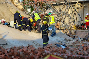 A rescue worker removes rubble from the site where construction workers are trapped under a building that collapsed in George, South Africa May 7, 2024.