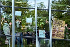 Students show messages from the windows of a building of Freie Universitat (FU) Berlin to the pro-Palestinian demonstrators as they occupy a courtyard with a protest camp, amid the ongoing conflict between Israel and Palestinian Islamist group Hamas, in Berlin, Germany, May 7, 2024.
