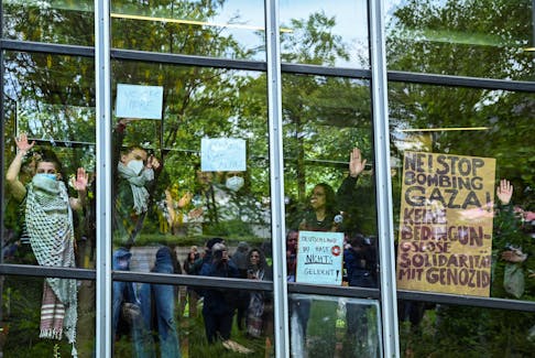 Students show messages from the windows of a building of Freie Universitat (FU) Berlin to the pro-Palestinian demonstrators as they occupy a courtyard with a protest camp, amid the ongoing conflict between Israel and Palestinian Islamist group Hamas, in Berlin, Germany, May 7, 2024.