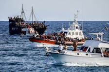 An Italian Coast Guard vessel carrying migrants rescued at sea passes between tourist boats, on Sicilian island of Lampedusa, Italy, September 18, 2023.