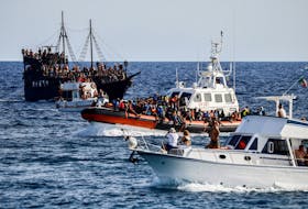 An Italian Coast Guard vessel carrying migrants rescued at sea passes between tourist boats, on Sicilian island of Lampedusa, Italy, September 18, 2023.