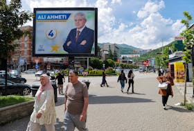 Pedestrians walk past campaign billboards for the upcoming parliamentary and presidential elections in Tetovo, North Macedonia May 7, 2024.