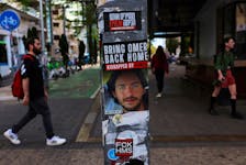 People walk past a poster of a hostage kidnapped during the deadly October 7 attack by Palestinian Islamist group Hamas from Gaza, pasted along with other items on a light pole in Tel Aviv, Israel, May 7, 2024.