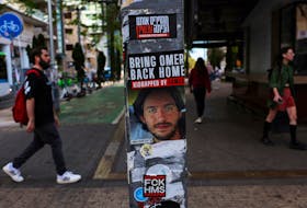People walk past a poster of a hostage kidnapped during the deadly October 7 attack by Palestinian Islamist group Hamas from Gaza, pasted along with other items on a light pole in Tel Aviv, Israel, May 7, 2024.