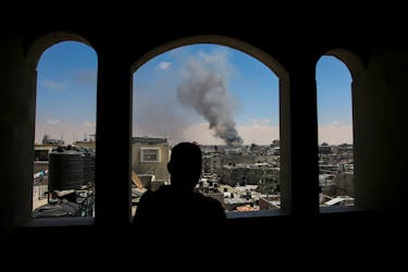 A Palestinian man watches as smoke rises after Israeli strikes while Israeli forces launch a ground and air operation in the eastern part of Rafah, amid the ongoing conflict between Israel and Hamas, in Rafah, in the southern Gaza Strip May 7, 2024.