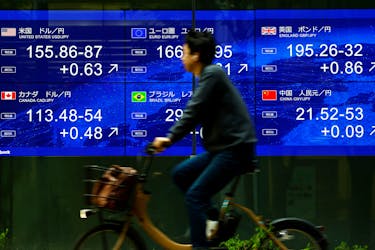 A man rides a bicycle past an electronic screen displaying the current Japanese Yen exchange rate against the U.S. dollar and other foreign currencies in Tokyo, Japan May 2, 2024,
