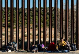 Asylum-seeking migrants from India wait by the border wall while waiting to be picked up by the U.S. Border Patrol after crossing the border from Mexico into the U.S. in Jacumba Hot Springs, California, U.S. April 27, 2024. 