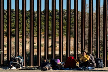 Asylum-seeking migrants from India wait by the border wall while waiting to be picked up by the U.S. Border Patrol after crossing the border from Mexico into the U.S. in Jacumba Hot Springs, California, U.S. April 27, 2024. 