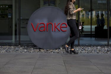 An employee walks past a logo of Vanke at its headquarters in Shenzhen, south China's Guangdong province, November 2, 2015.
