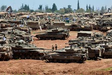 Israeli soldiers walk next to military vehicles near the Israel-Gaza border, amid the ongoing conflict between Israel and the Palestinian Islamist group Hamas, in southern Israel, May 8, 2024.