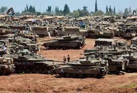 Israeli soldiers walk next to military vehicles near the Israel-Gaza border, amid the ongoing conflict between Israel and the Palestinian Islamist group Hamas, in southern Israel, May 8, 2024.