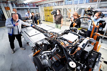 An employee explains the battery system and the engine of a fully electric VW ID Buzz to journalists on a production line at a Volkswagen Commercial Vehicle plant in Hanover, Germany, June 16, 2022.