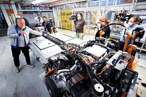 An employee explains the battery system and the engine of a fully electric VW ID Buzz to journalists on a production line at a Volkswagen Commercial Vehicle plant in Hanover, Germany, June 16, 2022.