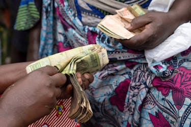 Clementine Musonge, a trader, counts Congolese francs bank notes at the Kituku market in Goma, North Kivu province of the Democratic Republic of Congo February 15, 2024.