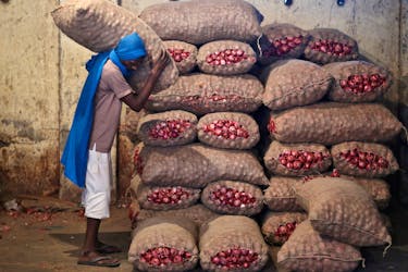 A labourer stacks a sack of onions in a storage room at a wholesale vegetable and fruit market in New Delhi July 2, 2014.