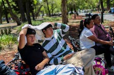 Men use a sweatshirt to protect themselves from the sun during a heat wave in Mexico City, Mexico April 16, 2024.