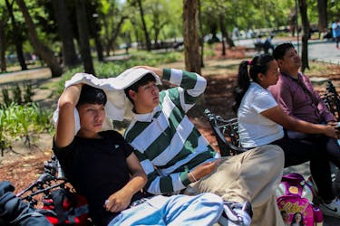 Men use a sweatshirt to protect themselves from the sun during a heat wave in Mexico City, Mexico April 16, 2024.