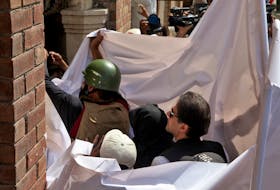 Pakistan's former Prime Minister Imran Khan and his wife Bushra Bibi are covered with a white sheet as they arrive to appear at the High Court in Lahore, Pakistan, May 15, 2023.