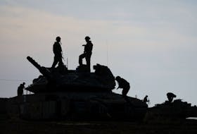 Israeli soldiers are silhouetted as they stand on a tank, near the Israel-Gaza border, amid the ongoing conflict between Israel and the Palestinian Islamist group Hamas, in Israel, May 2, 2024.
