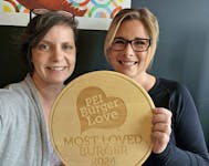 Danya O’Malley, left, executive director of P.E.I. Family Violence Prevention Services, presents the 2024 P.E.I. Burger Love champion plaque on May 8 to Danielle Casario, owner of The Seafood Shack in Morell. Casario said only at the convincing of her manager did she open up her business earlier than usual and enter Burger Love. The organization ran the campaign for the first time this year. Contributed