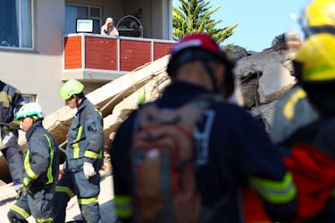 A resident watches as rescuers work to rescue construction workers trapped under a building that collapsed in George, South Africa May 8, 2024.