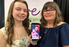 Monique Cashin and her daughter Bridget Claire hold a smartphone photo of Pat Cashin with Bridget Claire as a baby. Monique spoke Wednesday in Sydney at a donation presentation to the Cancer Care at Home campaign about how cancer research prolonged her husband's life. BARB SWEET/CAPE BRETON POST