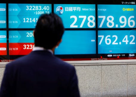 A man looks at an electronic board displaying Japan's Nikkei index outside a brokerage in Tokyo, Japan August 29, 2022.