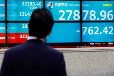 A man looks at an electronic board displaying Japan's Nikkei index outside a brokerage in Tokyo, Japan August 29, 2022.